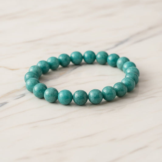 Jade green beaded bracelet arranged in a circular shape on light wooden surface, showcasing smooth, uniform spherical stones.