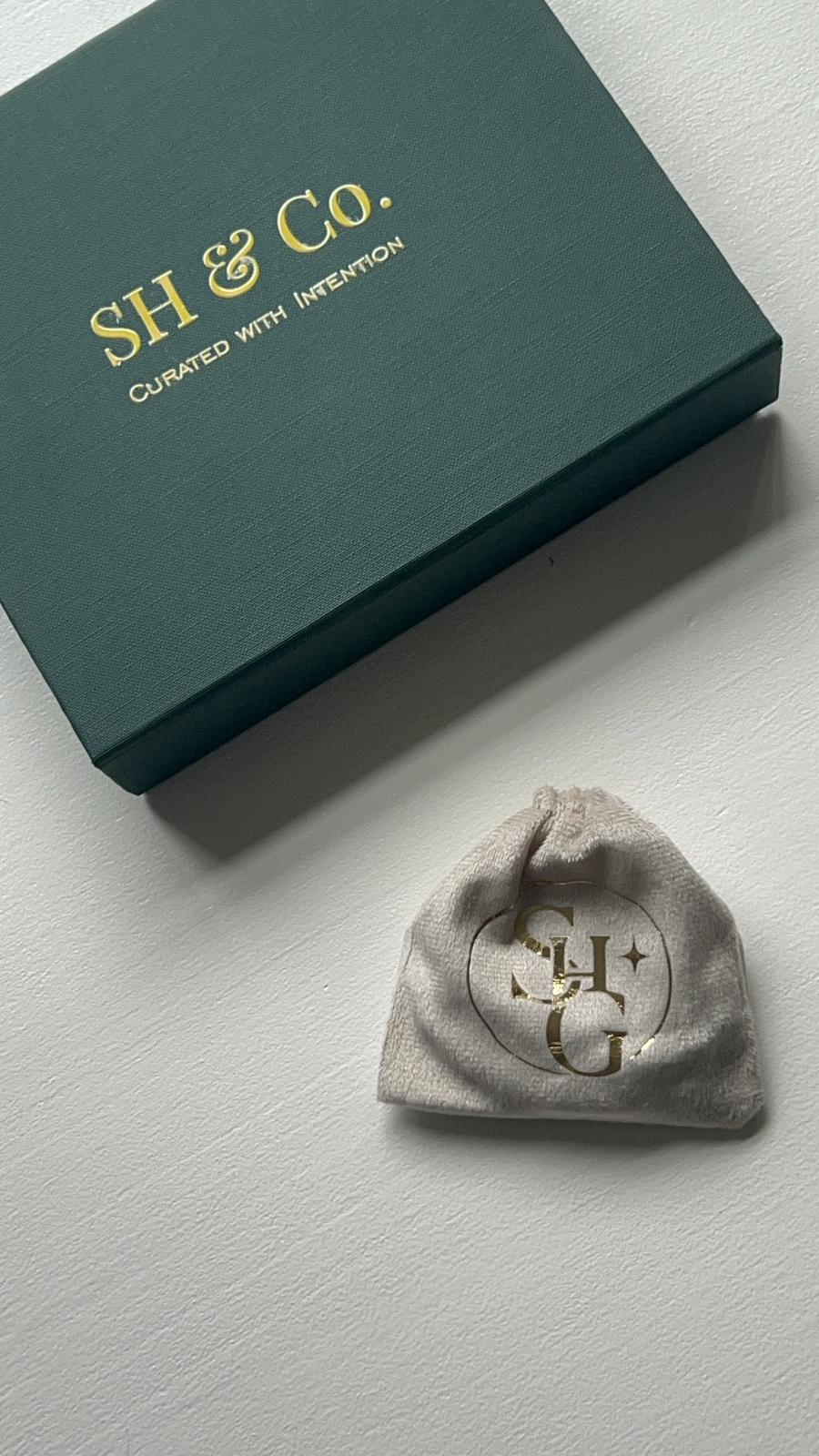 Velvet drawstring pouch with gold monogram beside the gift box