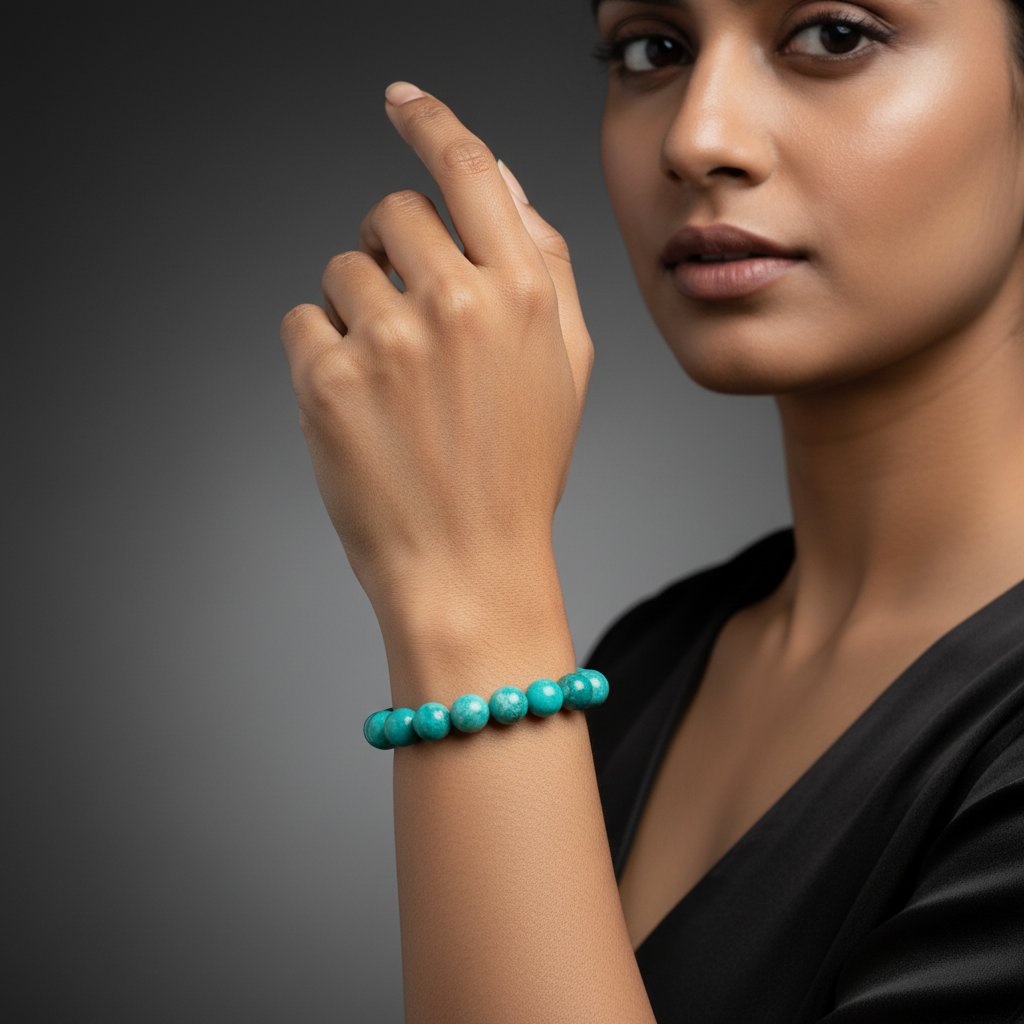 Turquoise beaded bracelet on wrist of person in black top against gray background